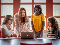 Students and instructor looking at a laptop